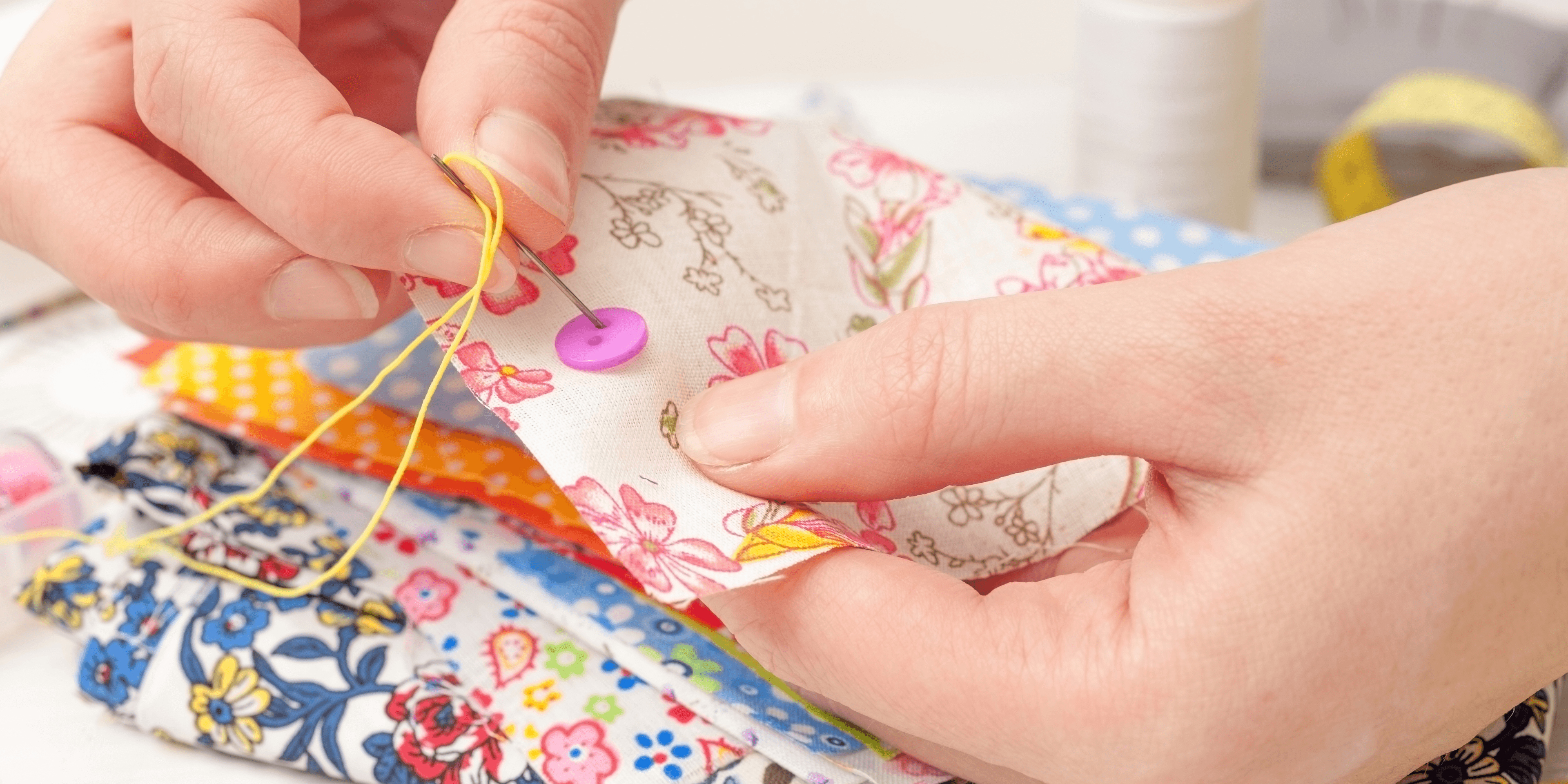 Hands sewing colorful fabric with buttons and thread